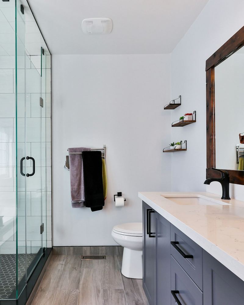 Bright renovated bathroom with a glass shower, wood-framed mirror and double vanity